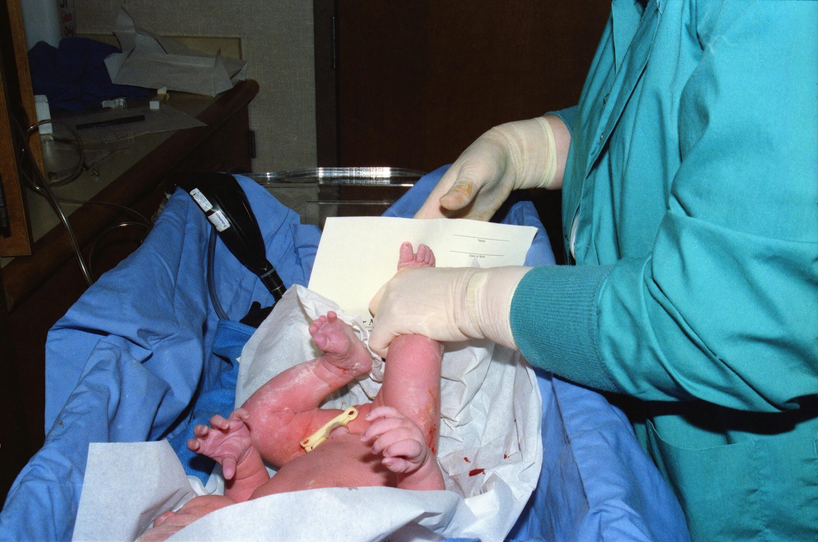 A nurse tends to a newborn baby in a hospital delivery room setting.